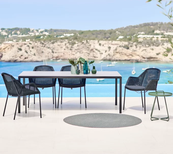 Der lavagraue Pure-Tisch zusammen mit schwarzen Breeze Sesseln von Cane-line.