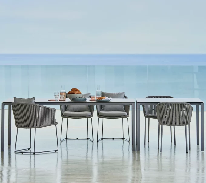 Der hellgraue Pure-Tisch in Kombination mit Moments-Sesseln von Cane-line.