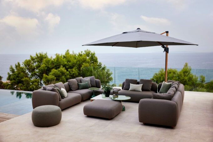 Capture-Lounge mit Circle-Hocker und Glaze-Tischen mit Hyde-Sonnenschirm, alles von Cane-line.