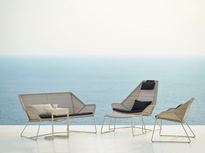 Die Breeze Serie von Cane-line mit Highback Sessel inklusive Hocker, Sofa und Lounge-Sessel in weiss/grau mit Time Out Beistelltisch.