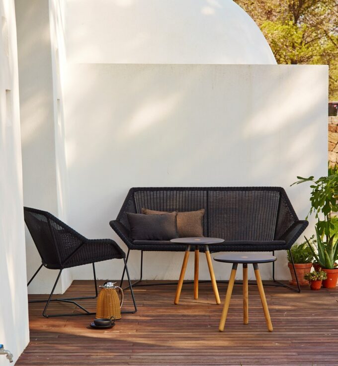 Der schwarze Breeze Loungesessel und das Sofa mit Area-Tischen von Cane-line.