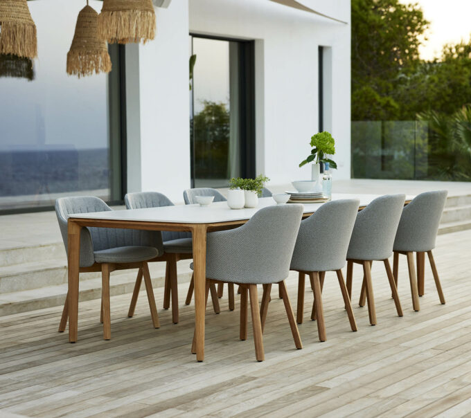 Von Cane-line: Grosszügiger 280 cm Aspect Tisch mit Travertine Platte und acht Choice Stühlen mit Teak Füssen und Focus Bezug.