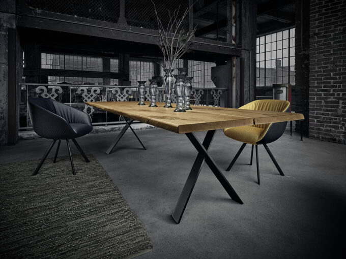 18Hundert Baumtisch mit schwarzem Kreuzfuss. Unikats-Tischplatte in massiver, rustikaler Asteiche. Kombiniert mit dem Schalenstuhl aus der 18Hundert Kollektion.