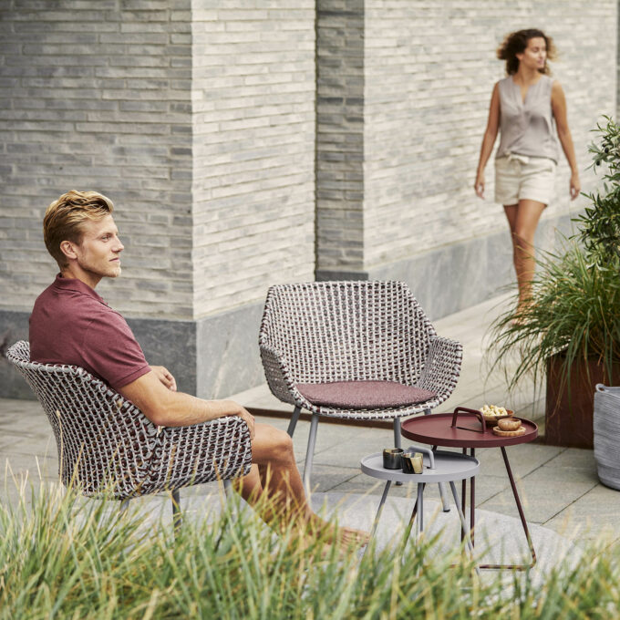 Von Cane-line der Vibe Loungesessel in hellgrau/bordeaux/dusty rose mit Wove Kissen in Dark bordeaux.